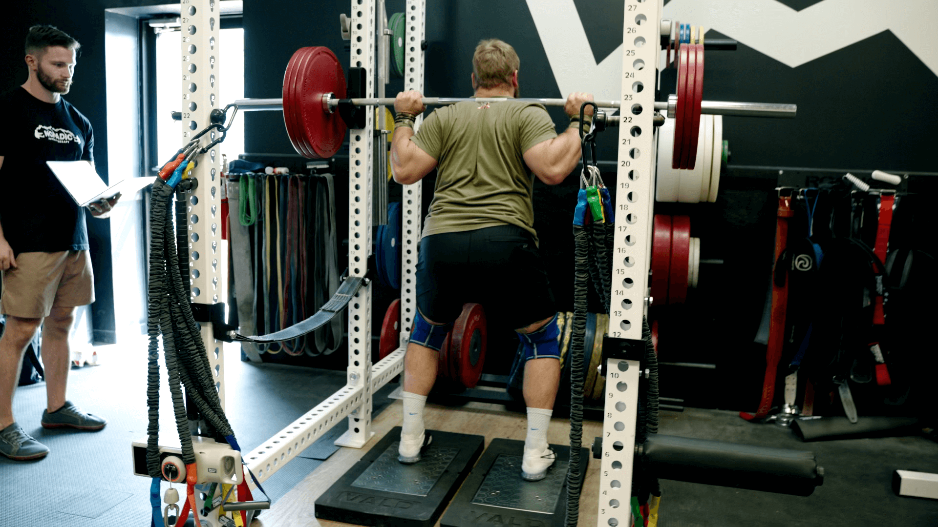 Wes setting up for his squat assessment on the ForceDecks, un-racking a weighted barbell from the squat rack.